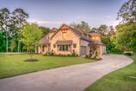 Elegant stone family home surrounded by trees, lush lawn, and vibrant garden.
